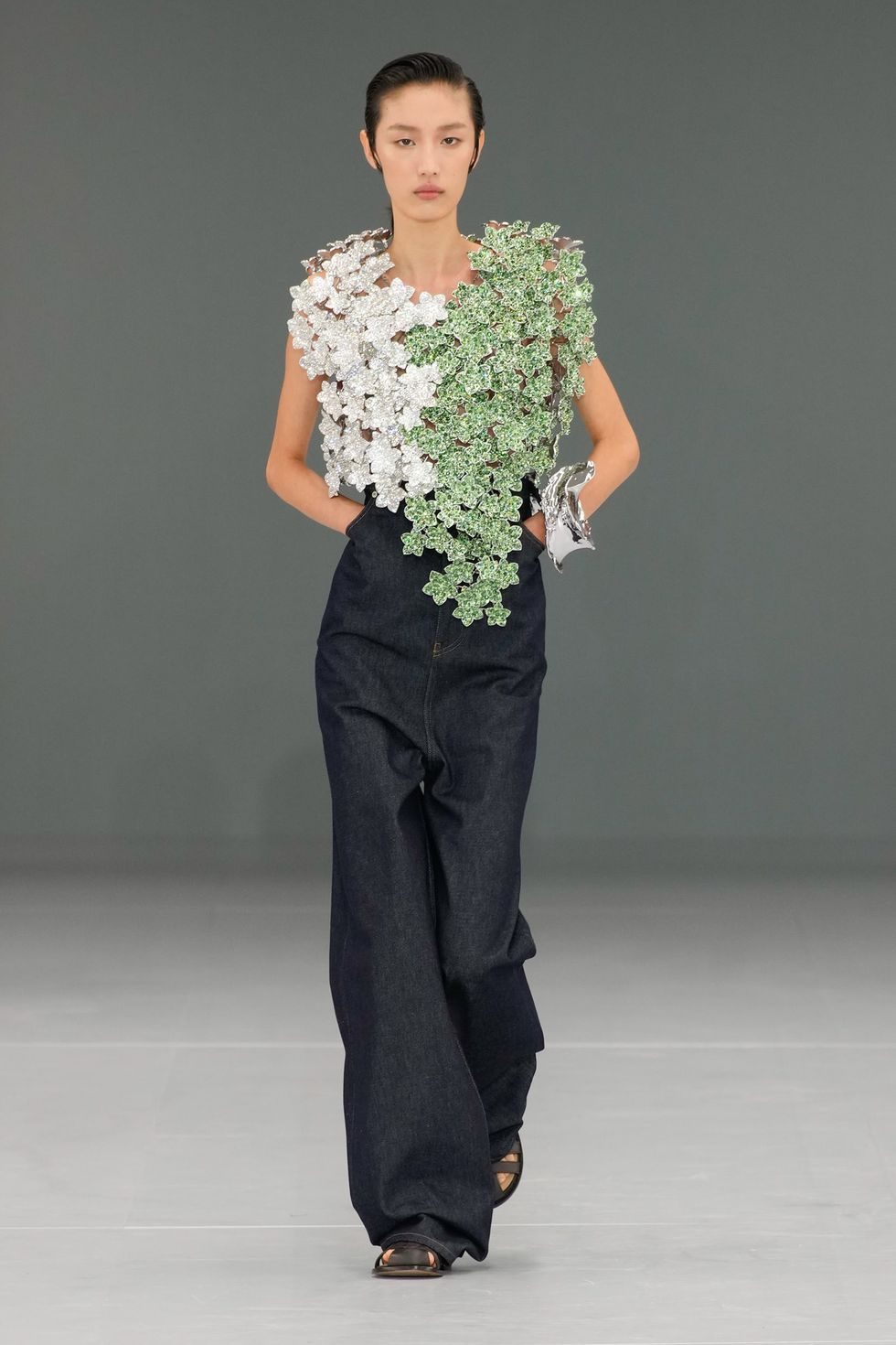 Model in a white and green top with decorative details at the show.