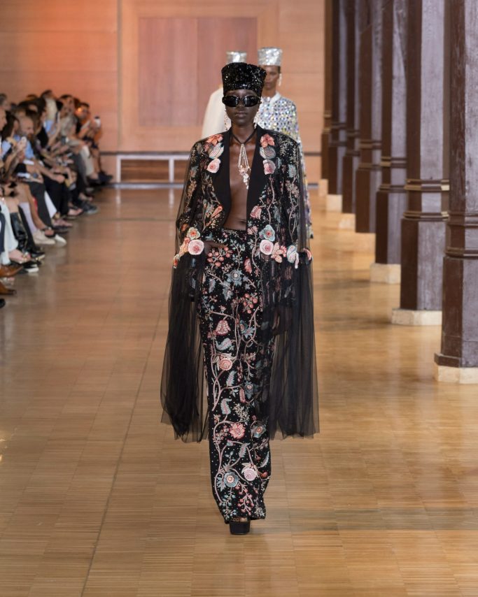 Model wearing a flowing black dress with glowing beadwork, evoking the energy of the cosmos.
