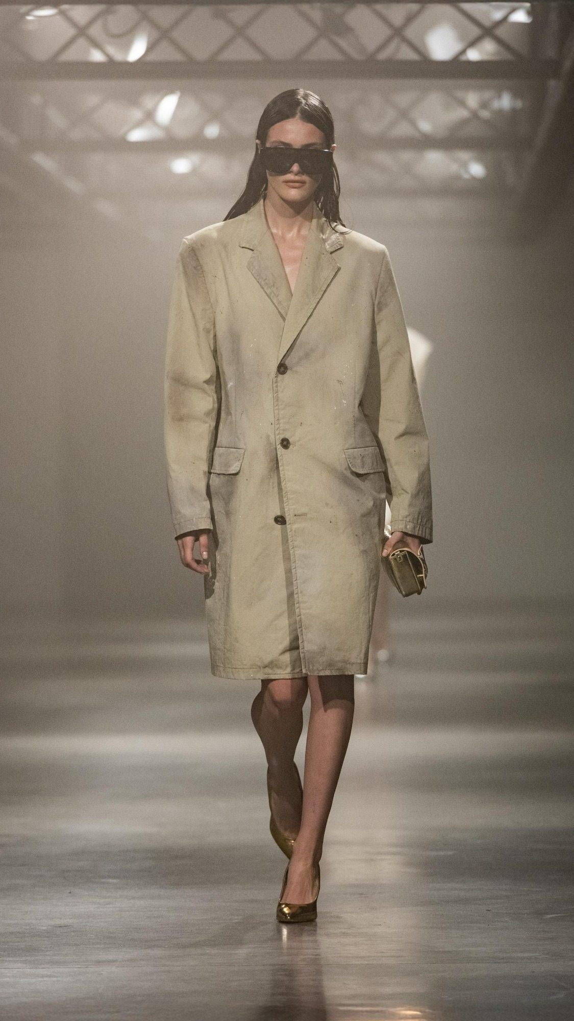 Model wearing an oversized trench coat with bold, geometric patterns.