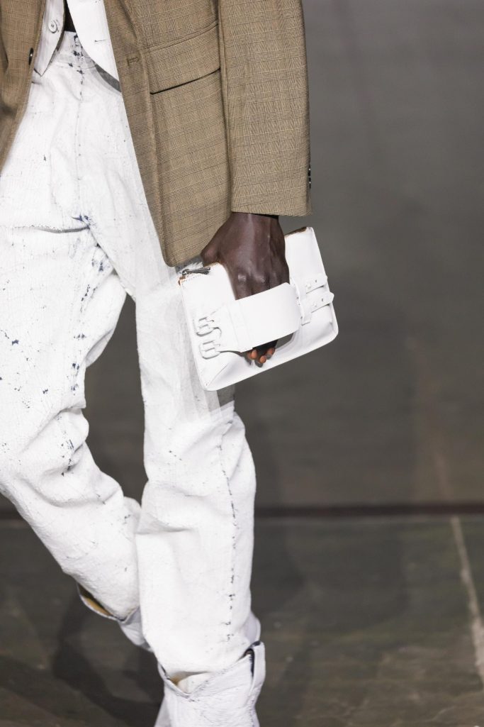 Model with chunky metal earrings and a deconstructed handbag.